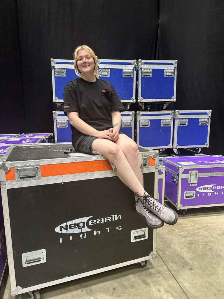 Lucy Primiano sitting on a Neg Earth Lights Flight Case.